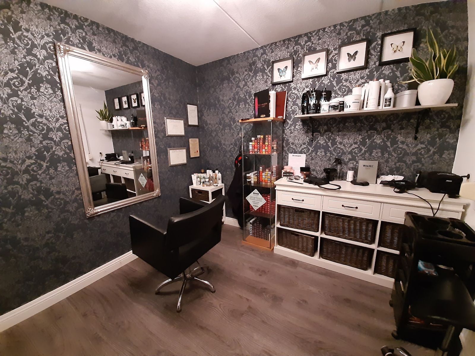 De salon: grote spiegel, zwarte kappersstoel en een witte kast met producten